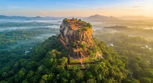 Sigiriya rock fortress rising above misty forest at sunrise