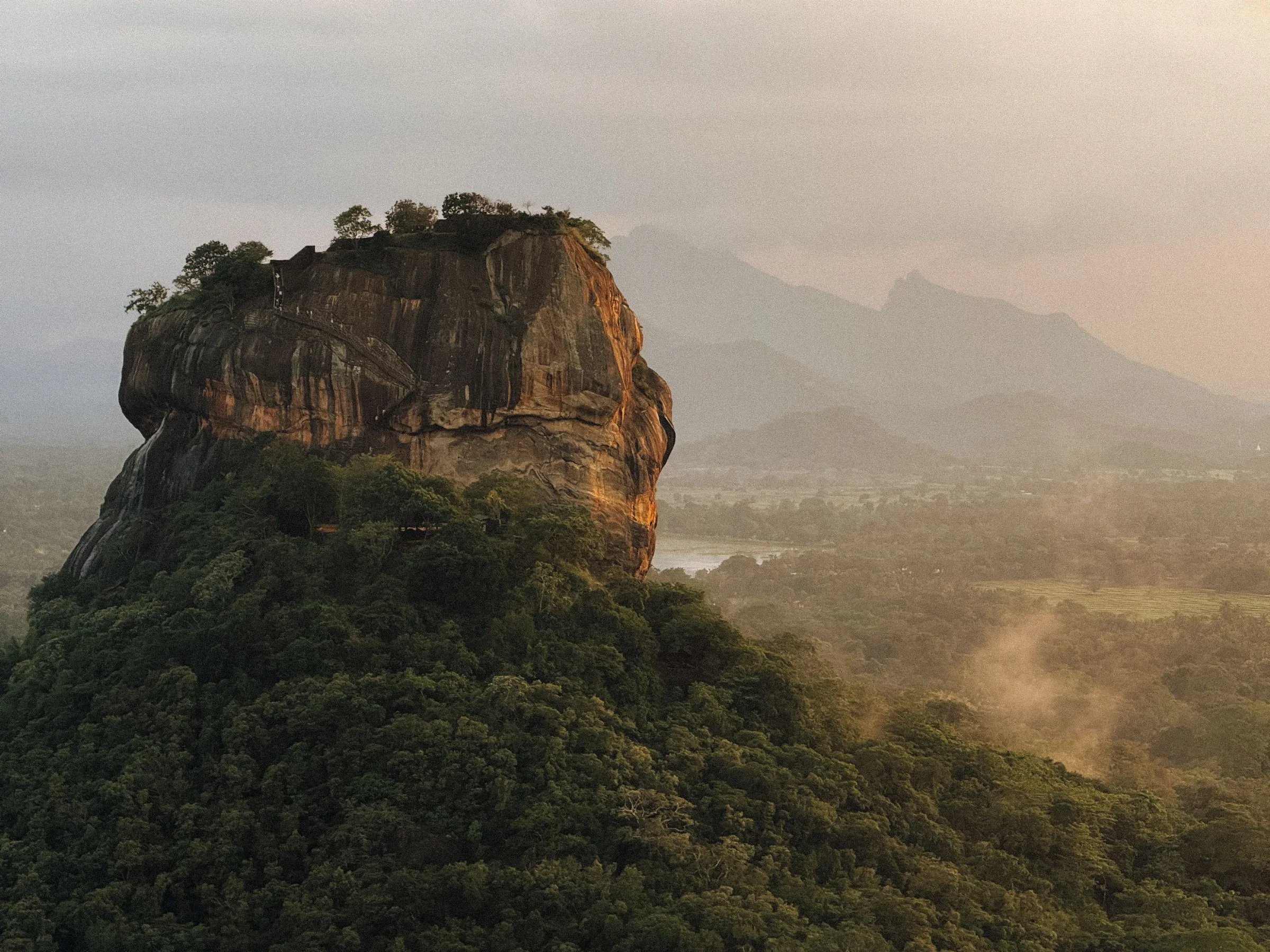 Sigiriya rock fortress rising above misty forest at sunrise